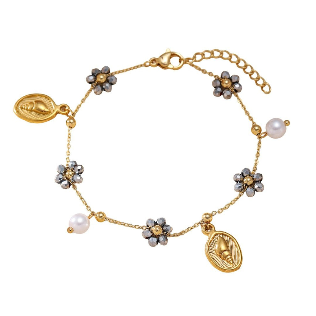 Bracelet doré en acier inoxydable avec charms fleurs noires et blanches et perles nacrées, fermoir mousqueton.