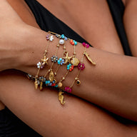 Bracelet doré en acier inoxydable avec charms soleil, fleurs colorées, coquillage et étoile de mer.