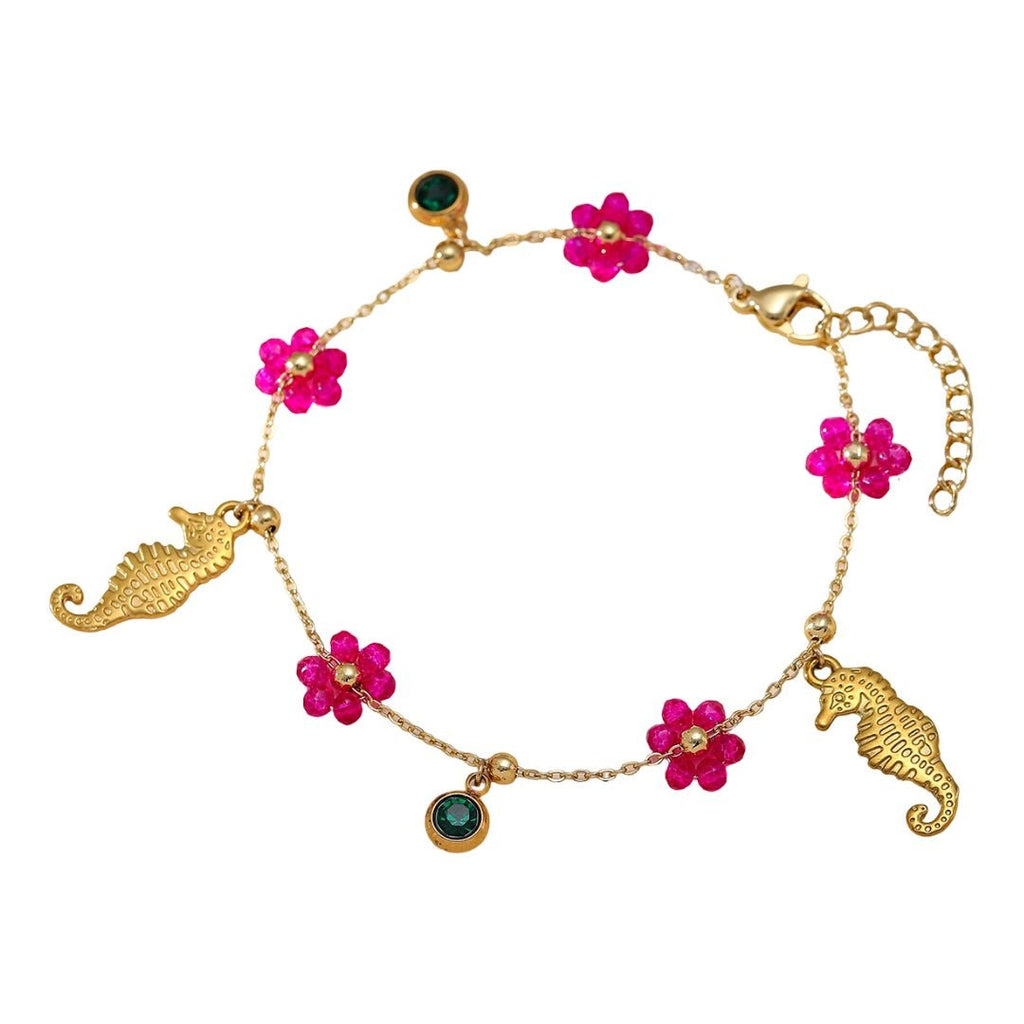 Bracelet doré en acier inoxydable avec charms hippocampe, fleurs roses et pierres vertes.