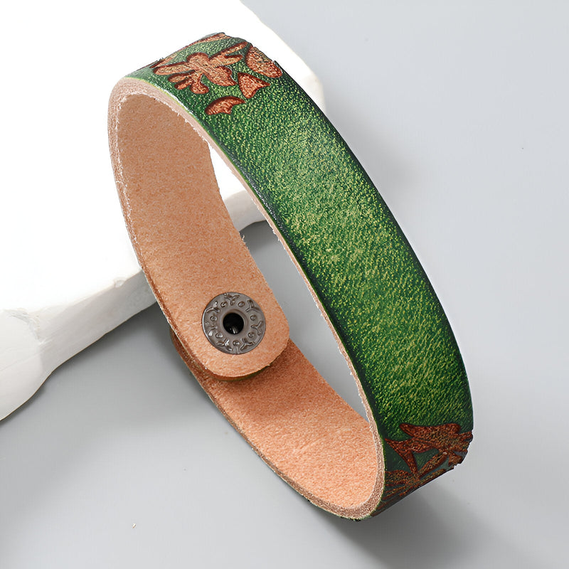 Bracelet en cuir vert avec motif floral marron et fermeture pression noire.