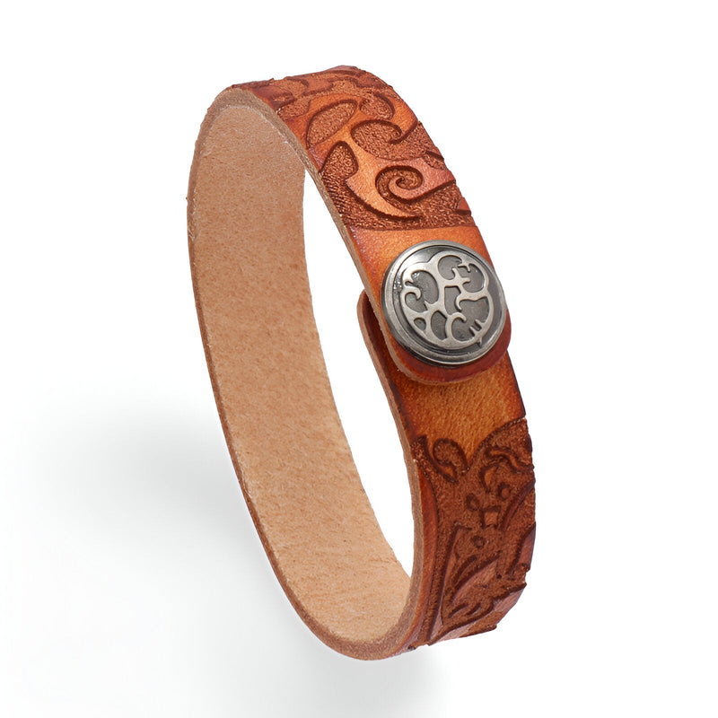 Bracelet en cuir cognac avec motif floral gravé et bouton métallique circulaire gravé.