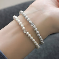 Bracelet pour femme en perles d'imitation blanches avec pierres brillantes, style chic et élégant.