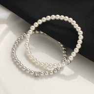 Bracelet chic en perles d'imitation blanches avec un détail strass élégant.