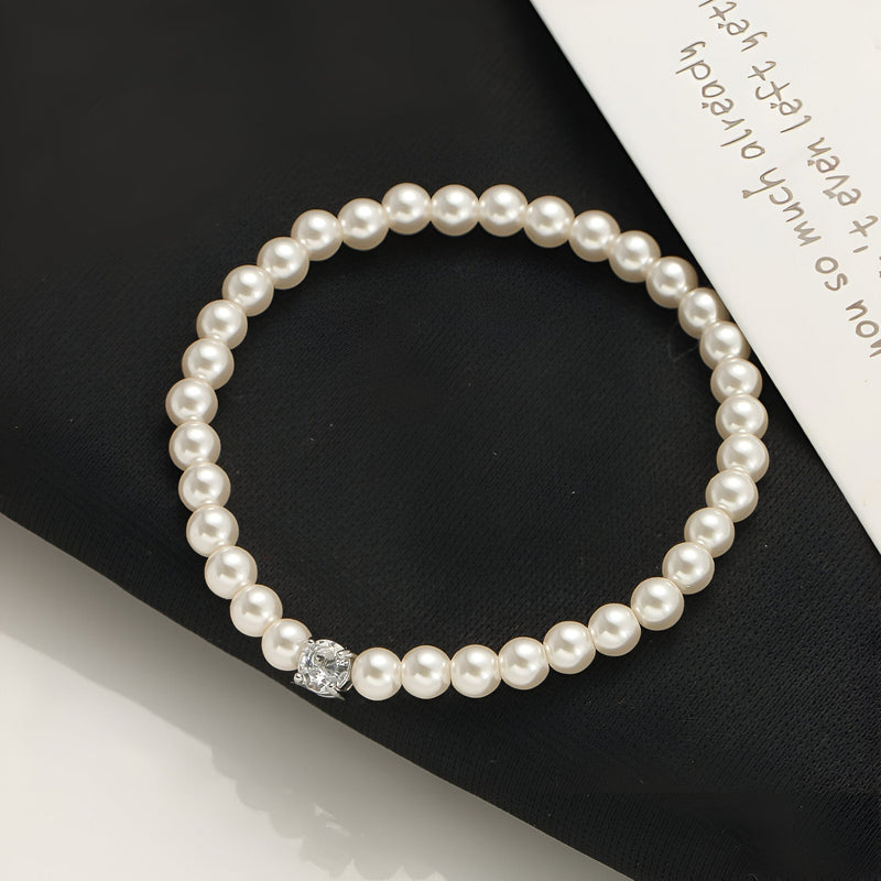 Bracelet chic en perles d'imitation blanches avec un petit pendentif en cristal circulaire.