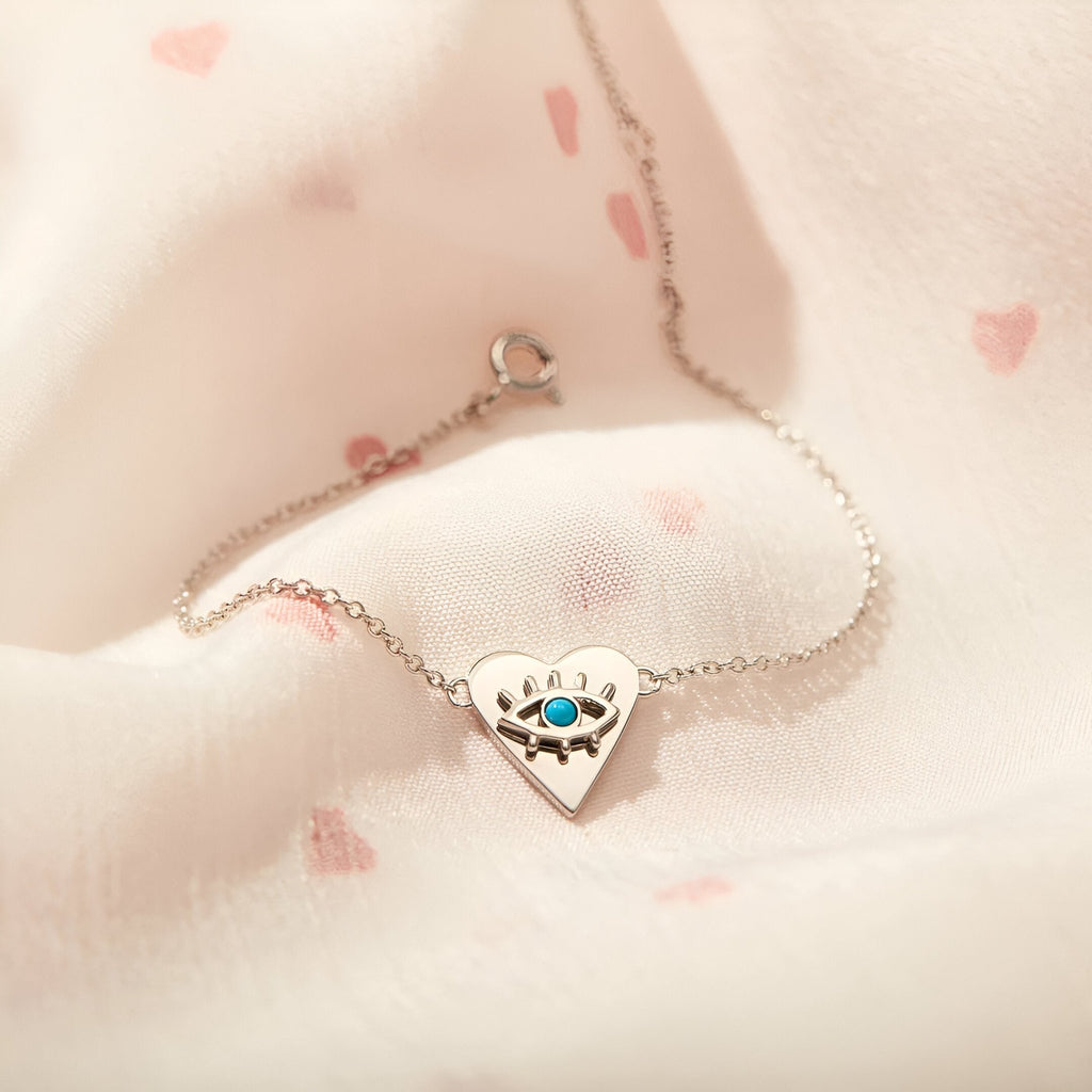 Bracelet en argent sterling avec pendentif cœur incrusté d’un œil bleu sur chaîne fine.
