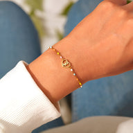 Bracelet en argent sterling avec pendentif cœur incrusté d'une rose, perles dorées fines.