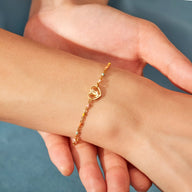 Bracelet fin en or avec pendentif cœur incrusté d'une petite rose délicate.