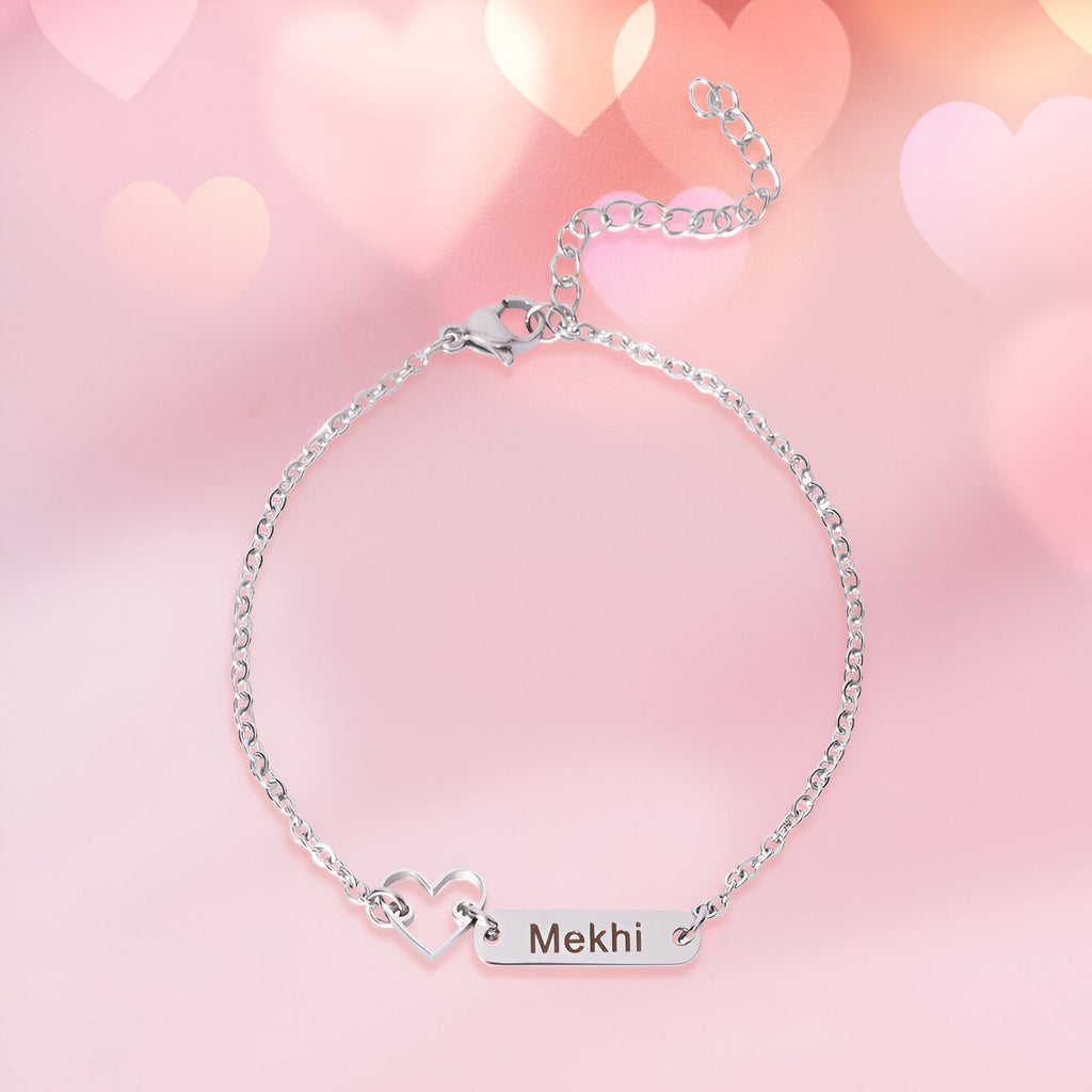 Bracelet fin en acier inoxydable argenté avec pendentif plaque gravée et cœur ajouré.