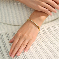 Bracelet fin plaqué or en acier inoxydable avec chaîne délicate sur poignet féminin.