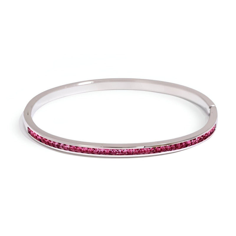 Bracelet rigide en acier inoxydable plaqué or avec fine rangée de cristaux rose fuchsia.