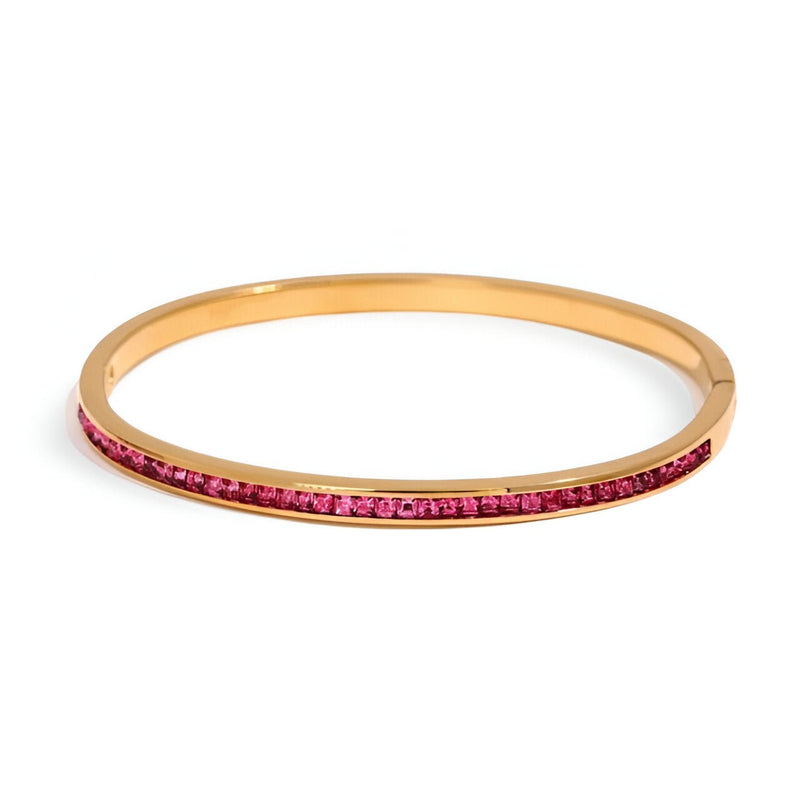 Bracelet fin plaqué or avec rangée de petites pierres rouges étincelantes, style élégant et minimaliste.