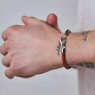 Bracelet en cuir marron avec crochet en acier inoxydable sur poignet masculin, style sobre et moderne.