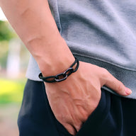 Bracelet cordon noir à double mousquetons pour homme porté au poignet.