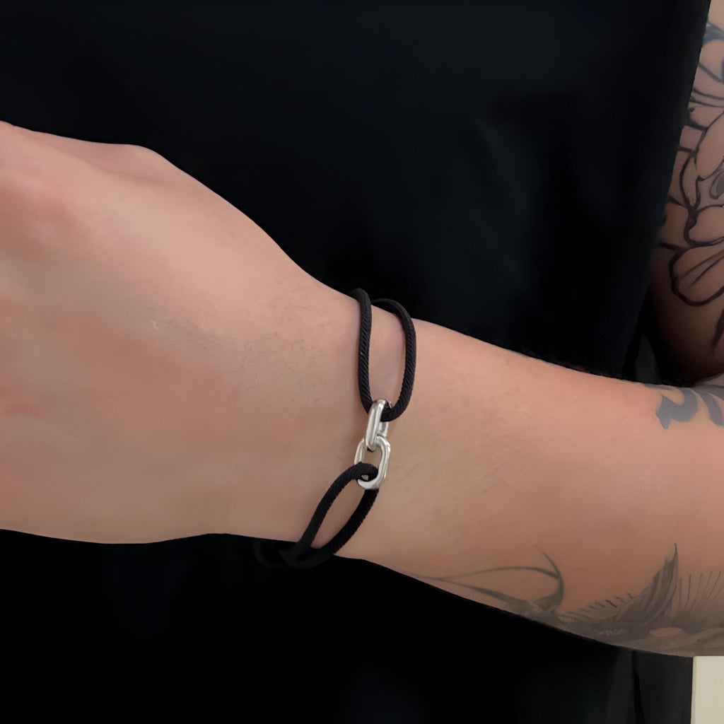 Bracelet cordon noir avec maillons croisés argentés, style minimaliste unisexe.
