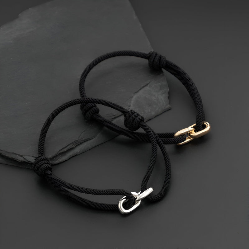 Bracelet cordon noir avec maillon croisé en métal argenté, style ajustable.