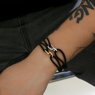 Bracelet cordon noir avec maillons croisés argent et or, style unisexe moderne.