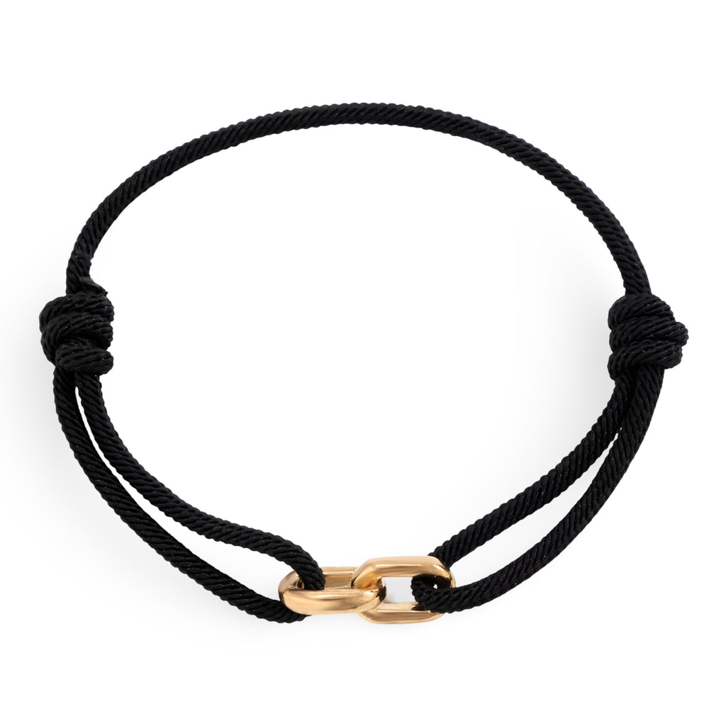 Bracelet cordon noir avec maillons croisés en métal doré, style minimaliste.