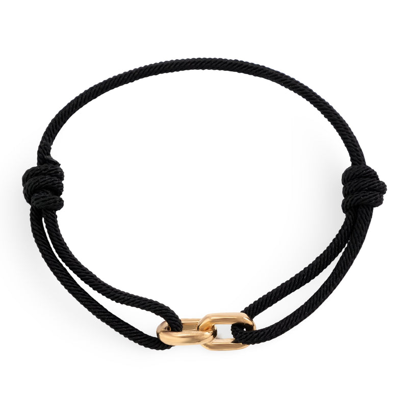 Bracelet cordon noir avec maillons croisés en métal doré, style minimaliste.