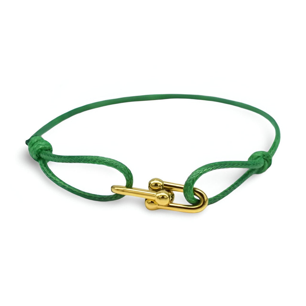 Bracelet cordon vert avec maillons croisés dorés et fermoir à tige élégante.