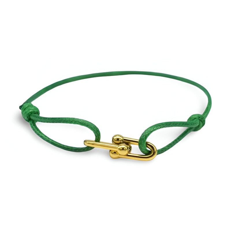Bracelet cordon vert avec maillons croisés dorés et fermoir à tige élégante.