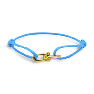 Bracelet cordon bleu ciel avec maillons croisés dorés et nœuds coulissants.