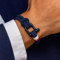 Bracelet cordon bleu marine avec manille noire et détail rouge et blanc, style nautique.
