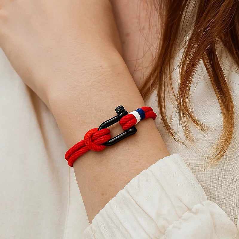 Bracelet cordon rouge à manille noire avec détail rouge et blanc, modèle Elmire, porté au poignet.