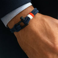 Bracelet cordon bleu marine avec manille noire et détail rouge et blanc, style nautique.