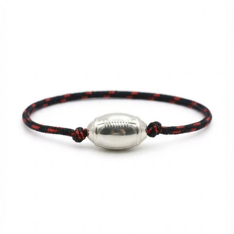 Bracelet cordon noir et rouge avec pendentif en forme de ballon de rugby argenté brillant.