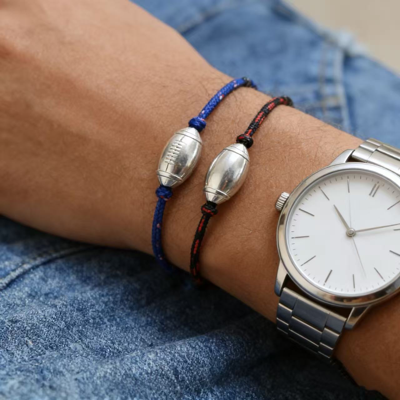 Bracelet cordon bleu et noir avec pendentif ballon de rugby en métal argenté, style sportif masculin.