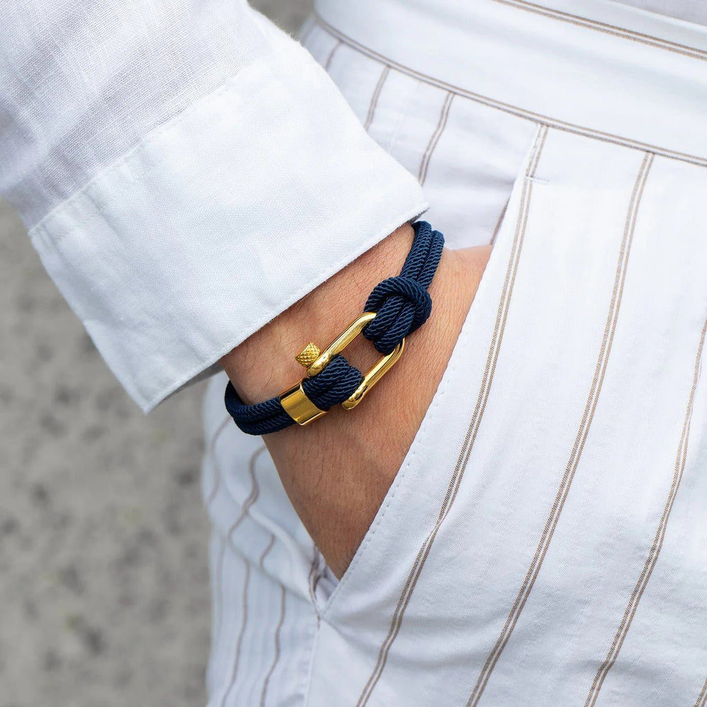 Bracelet cordon bleu marine avec mousqueton doré en acier inoxydable porté au poignet homme.