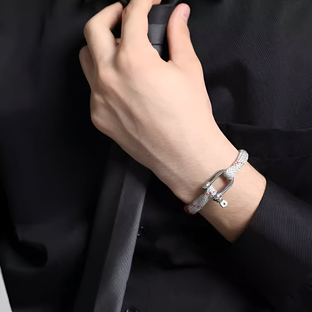 Bracelet cordon blanc avec mousqueton en acier inoxydable porté sur poignet homme en tenue noire.