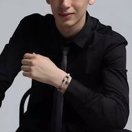 Bracelet cordon blanc avec mousqueton en acier inoxydable porté par homme en chemise noire.