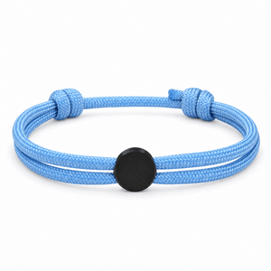 Bracelet Marsin Bleu clair et noir, cordon ajustable et pastille ronde, posé de face sur fond blanc