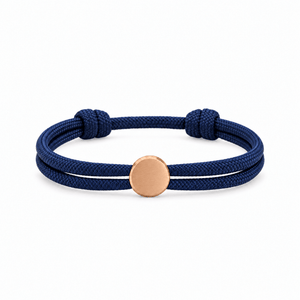 Bracelet Marsin Bleu marine et or rosé, cordon ajustable et pastille ronde, posé de face sur fond blanc