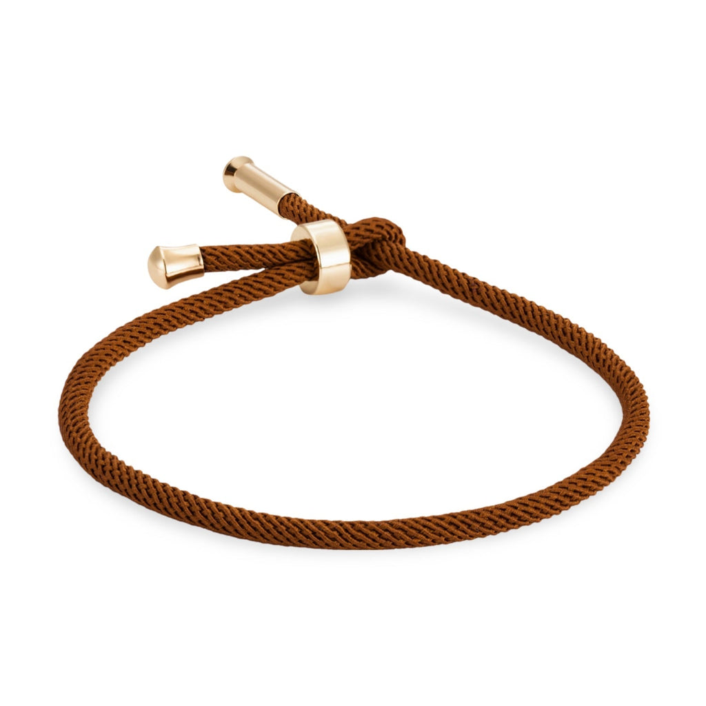 Bracelet cordon marron avec détails en titane plaqué or et fermoir minimaliste.