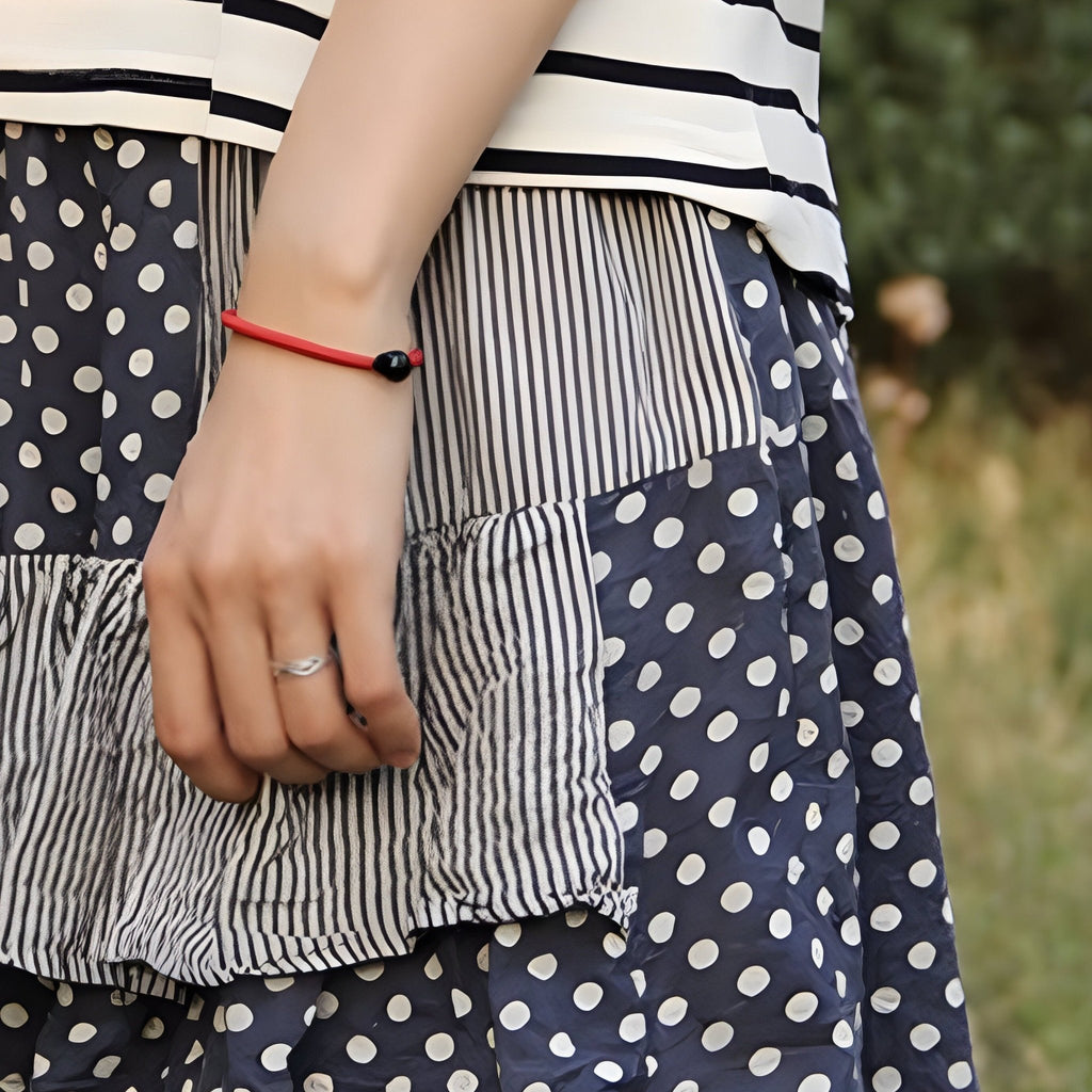Bracelet cordon rouge avec pierre d'agate noire ronde, style minimaliste pour femme.