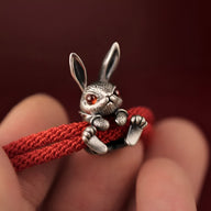 Bracelet cordon rouge avec charm lapin argenté aux yeux rouges détaillés.