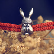 Bracelet cordon rouge avec charme lapin argenté aux yeux rouges au design détaillé.
