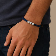 Bracelet cordon bleu marine avec plaque métallique gravée, style mixte, porté au poignet.