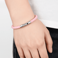 Bracelet cordon rose clair avec fermoir argenté sur poignet, style mixte et confortable.