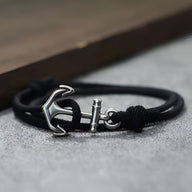 Bracelet cordon noir avec ancre marine en métal argenté et fermeture coulissante.