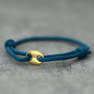 Bracelet cordon bleu avec fermoir circulaire doré au design minimaliste pour homme.