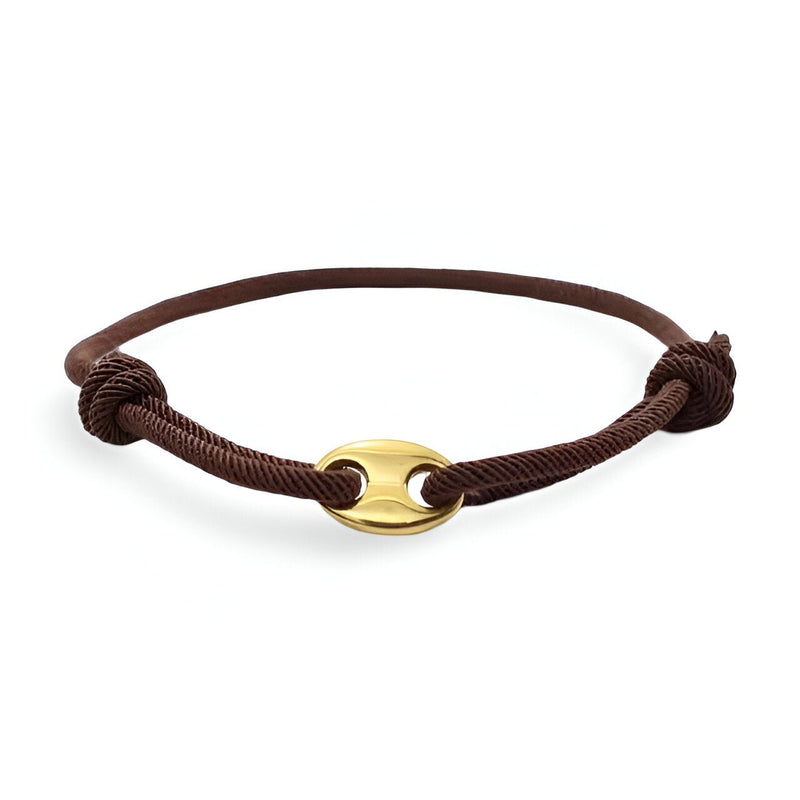 Bracelet cordon marron avec pendentif doré ovale et fermeture coulissante minimaliste.