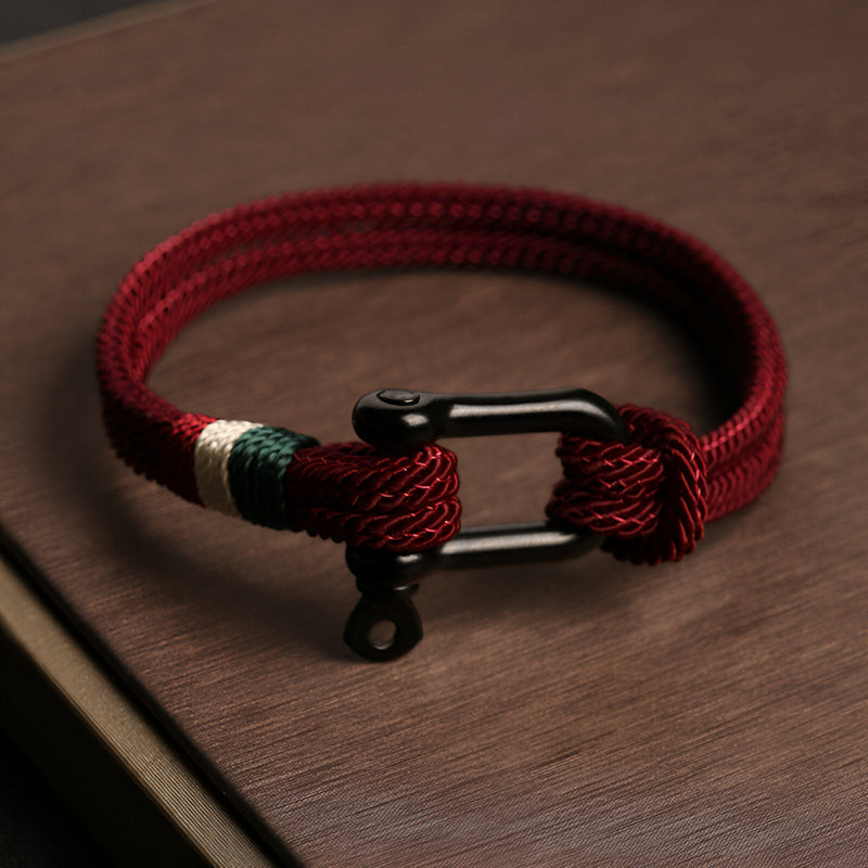 Bracelet cordon rouge avec mousqueton noir en acier inoxydable et détails tressés blancs et verts.