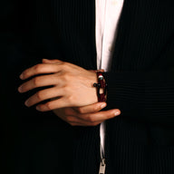 Bracelet cordon rouge avec mousqueton en acier inoxydable porté sur poignet d'homme.