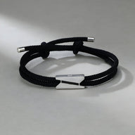 Bracelet cordon noir avec fermoir en titane argenté, design épuré et moderne pour homme.