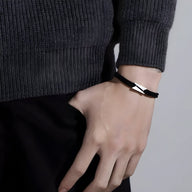 Bracelet cordon noir avec détail en titane brossé, design épuré pour homme.