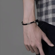 Bracelet cordon noir avec détail en titane minimaliste porté au poignet homme.