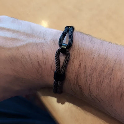 Bracelet cordon double bi-colore noir et marron avec nœud coulissant sur poignet homme.